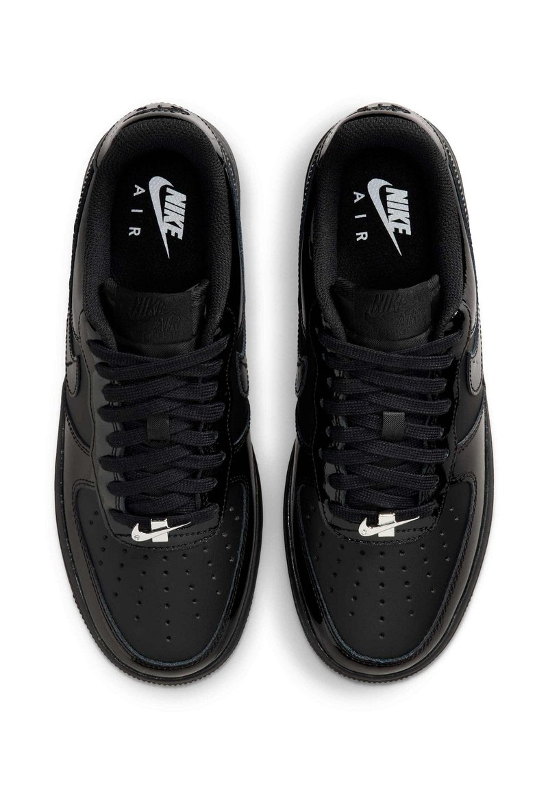 Par de zapatillas Nike Air negras vistas desde arriba, con cordones y pequeños logotipos plateados de Nike en la puntera y la plantilla.