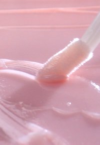 Lichtroze cosmetische crème met een zachte textuur, aangebracht met een pluizige applicator, met een glad oppervlak en subtiele glans.