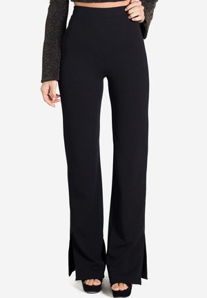 Pantalons évasés noirs taille haute avec fentes latérales, fabriqués en tissu extensible. Texture lisse, ajustés au niveau des hanches, design à jambes larges.