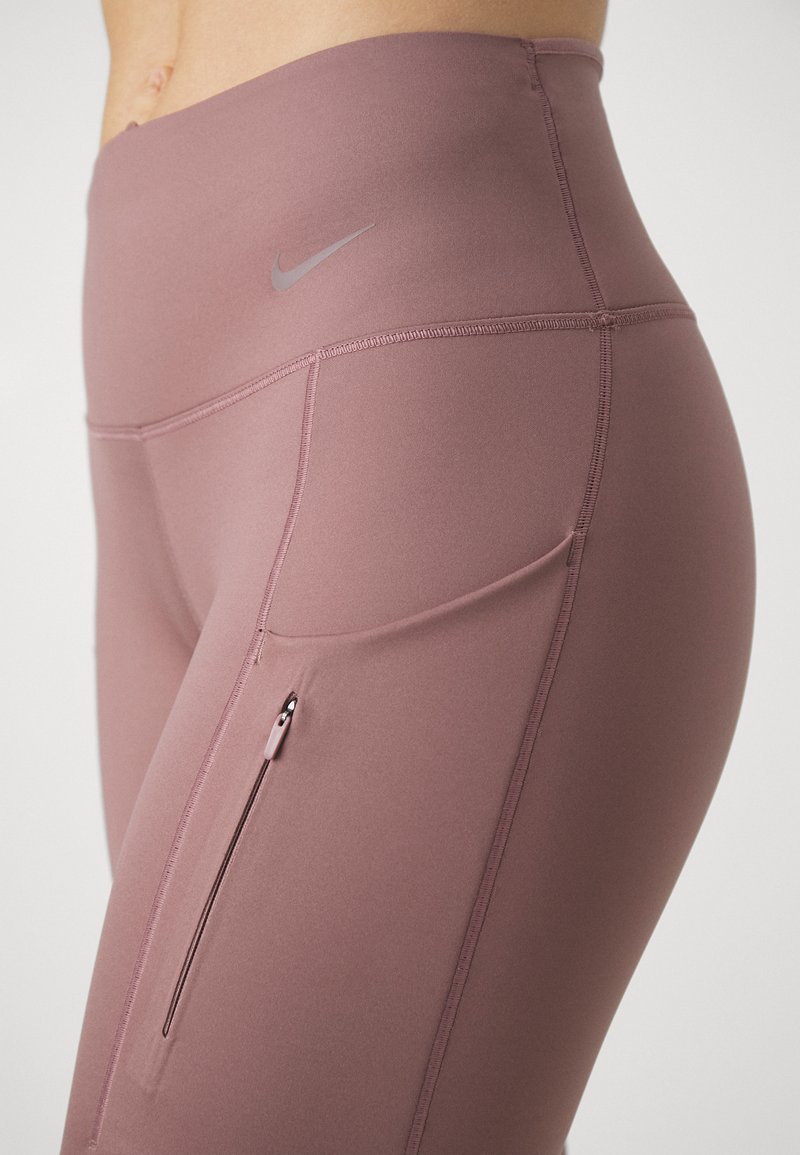 Leggings deportivos de cintura alta en color rosa polvo, hechos de una tela elástica, con un bolsillo lateral con cremallera y un discreto detalle de logo.