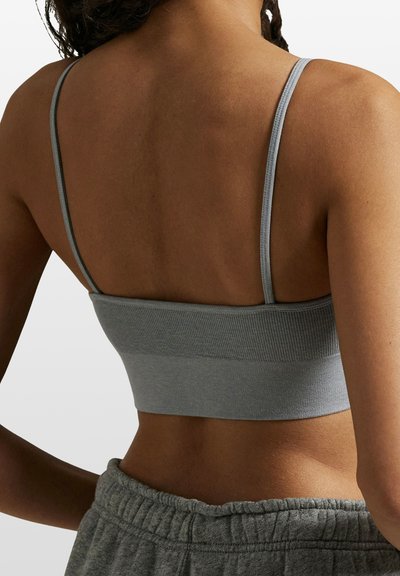 Szary krótki biustonosz z cienkimi ramiączkami, prążkowaną teksturą i szerokim pasem u dołu. Zaprojektowany z myślą o komforcie i dopasowaniu.