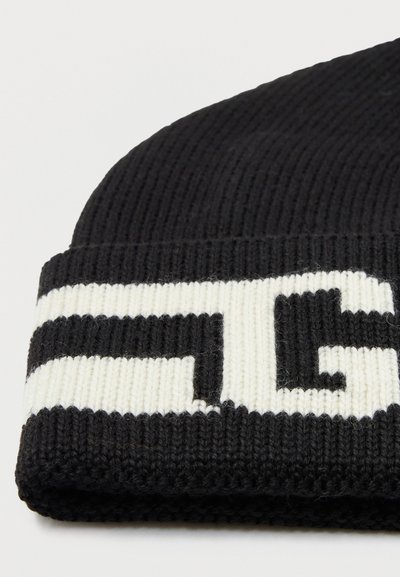 Gorro de punto negro con textura acanalada y un dobladillo doblado que presenta un prominente patrón de logo en blanco.