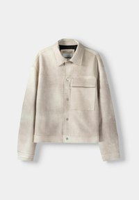 Beige mokkanahkatakki kauluksella, painonapillinen suljenta ja etutasku. Leikattu lyhyeksi ja siinä on hienovarainen tekstuuri.