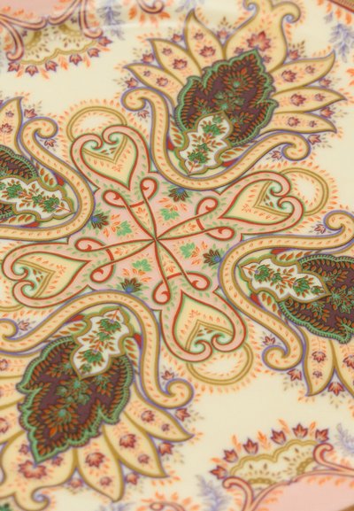 Motif floral et cachemire symétrique et complexe avec des détails verts, orange, violets et bruns sur un fond crème.