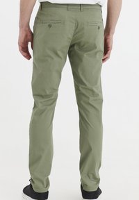 Olivno zeleni hlače s slim fit krojem, z zadnjimi žepi s gumbom in gladkim materialom iz mešanice bombaža.