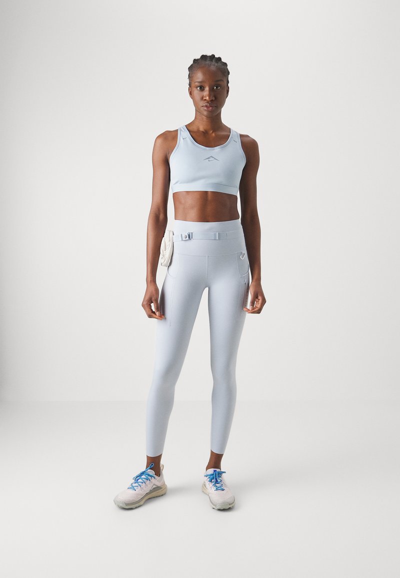 Crop top de sport bleu clair et leggings en tissu évacuant l'humidité, avec une taille haute et des poches latérales décoratives.