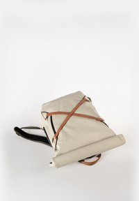 Rucksack mit einem beigen Canvas-Körper, braunen Lederakzenten, Schultergurten und einem aufgerollten Design. Verfügt über einen Reißverschluss und verstellbare Riemen.