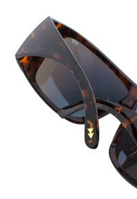 Bruna sköldpaddsglasögon med mörka linser, geometrisk ramar och subtila gyllene triangulära detaljer på skalmen.