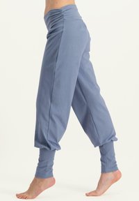 Ljust blå joggerbyxor med en rynkad midja, avsmalnande ankle cuffs och ett mjukt, texturerat tyg. Har en lös passform vid låren.