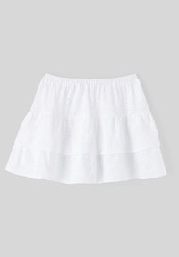 Jupe blanche à couches avec taille élastique et texture en broderie anglaise, ornée de petits détails en œillets.