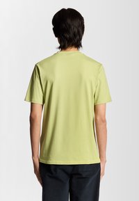 Lys grøn bomulds t-shirt med rund halsudskæring og korte ærmer, der har en glat tekstur og et enkelt design.
