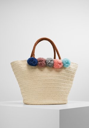 Beżowa pleciona torba z trawy z brązowymi owiniętymi rączkami i pięcioma kolorowymi pomponami w kolorach niebieskim, różowym, szarym, koralowym i turkusowym wzdłuż górnej krawędzi.