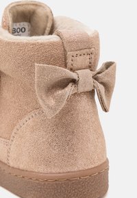 Brown suede ankle boot with a soft faux-fur lining, featuring a small glittery bow accent and textured rubber sole.