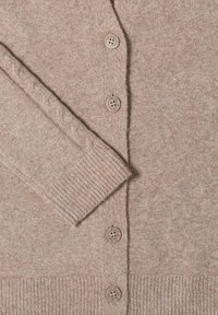 Beige stickad cardigan med ribbade muddar och nederkant, med fem bruna knappar och en kabelstickad detalj på ärmen.