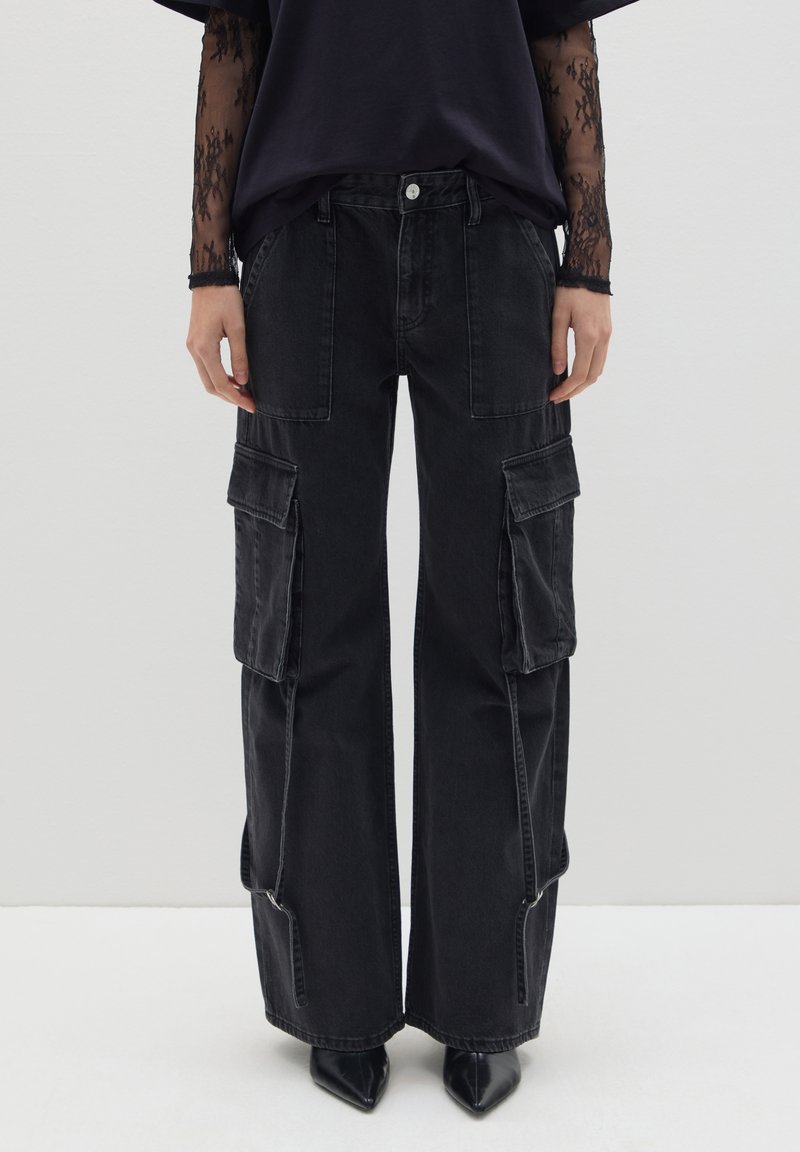 Pantalones cargo negros con un diseño de pierna ancha, que cuentan con múltiples bolsillos frontales, un ligero desvanecimiento y detalles de cremallera en el dobladillo.