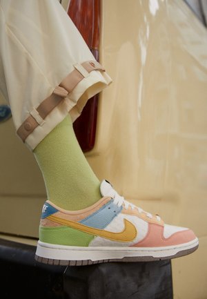 Nike Dunks med en flerfärgad design med persika, blå, gul och grön paneler. Vita läderdetaljer, texturerade accenter, gummisula.