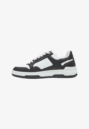 Svart og hvit sneaker med læroverdel, polstret krage og gummisåle med teksturert mønster. Snøring.