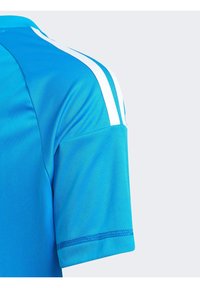 Kortärmad sportskjorta i klarr blått tyg, med vita ränder på axlarna och en sydd fåll. Slät textur med rundad halsringning.