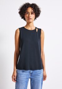 Top senza maniche di colore nero con scollatura rotonda e dettaglio a occhio di bottone sulla spalla. Realizzato in tessuto liscio; abbinato a jeans blu chiaro.