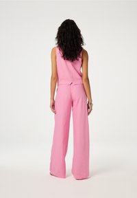 Roze twee-delige outfit met een mouwloos topje en een wijde broek, gemaakt van lichtgewicht stof met een licht gestructureerde afwerking.