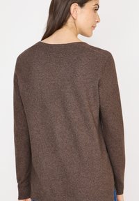 Brązowy sweter z dzianiny z okrągłym dekoltem, długimi rękawami i ściągaczami. Charakteryzuje się miękką fakturą i luźnym krojem z tyłu.