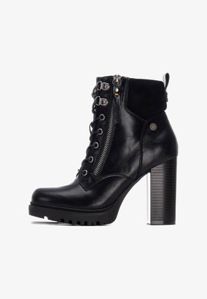 Botín negro de cuero y ante, con un alto tacón cuadrado, cordones en la parte delantera, cremallera lateral y suela de goma texturizada.