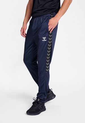 Marineblauwe sportbroek met zwart chevronpatroon aan de zijkant, elastische tailleband en Hummel-logo op het linkerbeen. Gemaakt van een gladde stof.