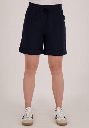 Marineblauwe shorts met een elastische tailleband, omgeslagen zoom en zijzakken, gemaakt van een soepele, lichte stof. G gedragen met witte sneakers.