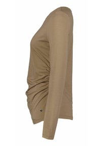Haut beige à manches longues avec fronces sur le côté et petit logo métallique près de l'ourlet, vu de profil gauche.