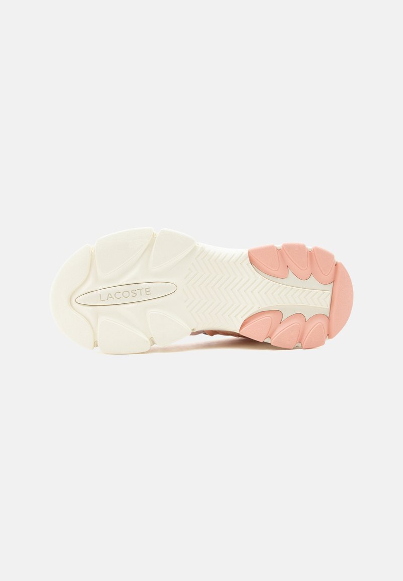Suola di una sneaker Lacoste con battistrada bianco e grip in gomma rosa nelle zone del tallone e della punta su sfondo bianco.