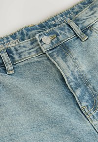 Svetlomodré denimmové šortky s voľným strihom, viditeľným šitím a strieborným zapínaním na gombík. Tkanina má mierne ošúchanú textúru.