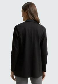 Zwarte blazer met krijtstreep, gestructureerd ontwerp, enkele knoopsluiting, mouwen van gemiddelde lengte, achterventilatie, gladde textuur, veelzijdige pasvorm.