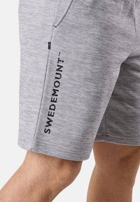 Harmaat urheilu shortsit, joissa on teksturoitu kangas, sivutasku ja musta "SWEDEMOUNT™" -teksti lahkeessa sekä pieni Ruotsin lipun yksityiskohta.