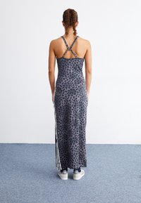 Leopardikuvioinen mekko, jossa on istuva siluetti, harmaan sävyjä, ristiin menevät olkaimet ja sivuraidat. Yhdistetty valkoisiin tennareihin.