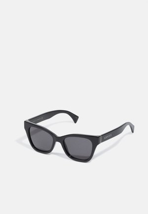Occhiali da sole rettangolari neri con finitura lucida, lenti scure e un accento dorato sulle tempie con il nome del marchio "GUCCI."