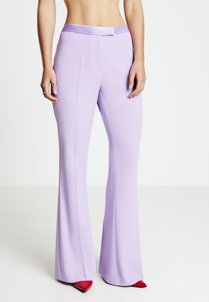 Pantaloni a zampa in lilla con una texture liscia, una vita aderente e dettagli a cucitura frontale, abbinati a décolleté rosse a punta.