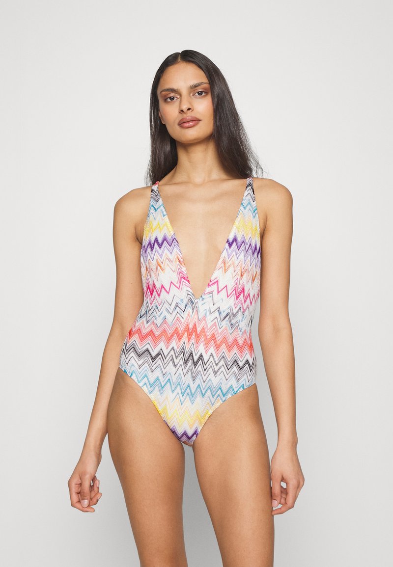 Šareno kupaćie s naljepnicom u cik-cak uzorku s dubokim V-izrezom, izrađeno od rastezljive tkanine. Sadrži više živopisnih boja uključujući ružičastu, plavu i žutu.