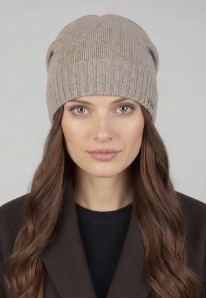 Dzianinowa czapka z dzianiny w jasnobeżowym kolorze z żebrowanym wzorem, z podwijanym mankietem i małym metalowym akcentem z boku. Miękka tekstura.