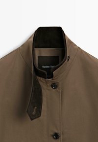 Giacca leggera marrone con colletto a coste, bottoni a pressione e una texture liscia. Presenta un'etichetta con "Massimo Dutti" all'interno.