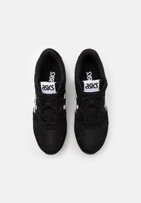 Czarne buty sportowe z siateczkową cholewką, z białymi akcentami i sznurowadłami. Logo wyraźnie widoczne na języku buta.