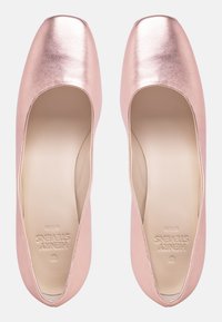 Rose gold ballet flats with a shiny finish, rounded square toe, and smooth interior. Labeled "Henry Street," designed with minimal accents.