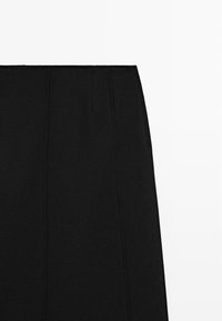 Black skirt with a straight design, made from a textured fabric. Features pleats at the top for detail. Smooth surface without patterns.