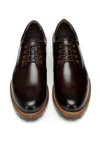 Brązowe skórzane buty o gładkim wykończeniu, zaokrąglonym nosku i sześcioma oczkami na sznurowadła. Charakteryzują się kontrastową jasnobrązową podeszwą i przeszyciami.