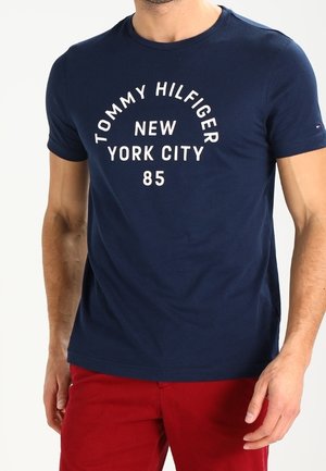 Navyblauwe katoenen t-shirt met in witte gebogen tekst "TOMMY HILFIGER NEW YORK CITY 85". Korte mouwen en ronde hals.