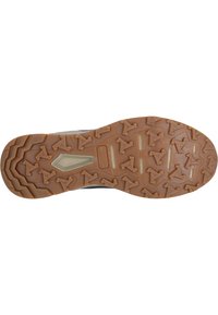 Trail running sko med en strukturerad, brun gummisula som har vinkelräta klackar för grepp och en ljust färgad mellansula.