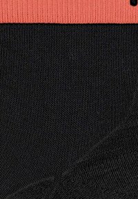 Czarne skarpetki z teksturowanym wzorem dzianiny, z solidnym koralowym ściągaczem na górze.