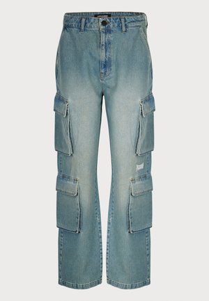 Jasnoniebieskie dżinsowe spodnie cargo mają wiele bocznych kieszeni, szeroki krój nogawek i lekko postarzony wygląd materiału.