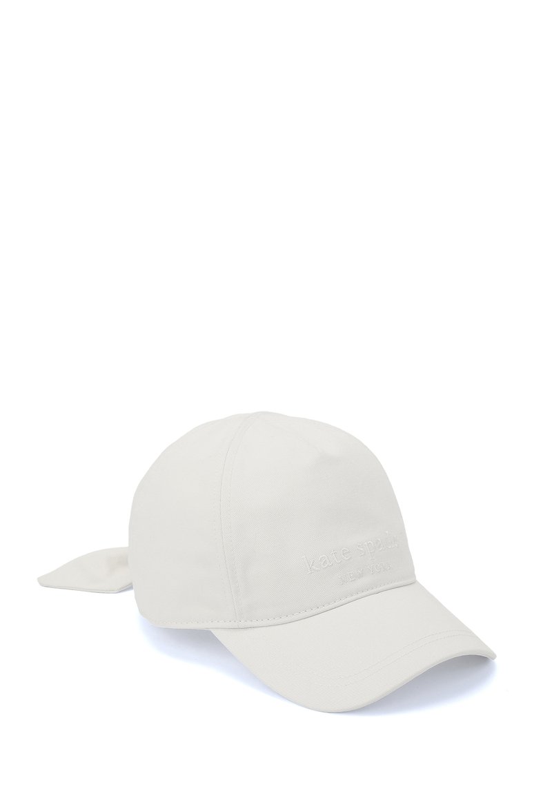 Ljusbeige keps med en böjd skärm, tygband bak och präglat varumärkesnamn "kate spade NEW YORK" på framsidan.