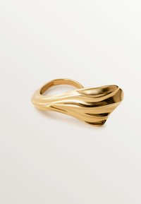 Anillo de oro con un diseño fluido que presenta formas suaves y curvadas, y acentos texturizados, mostrando un acabado metálico pulido.