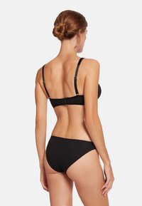 Svart bikini-set som har en mjuk bh med justerbara band och knäppning bak, i kombination med en matchande lågrisk bikiniunderdel. Minimalistisk design.